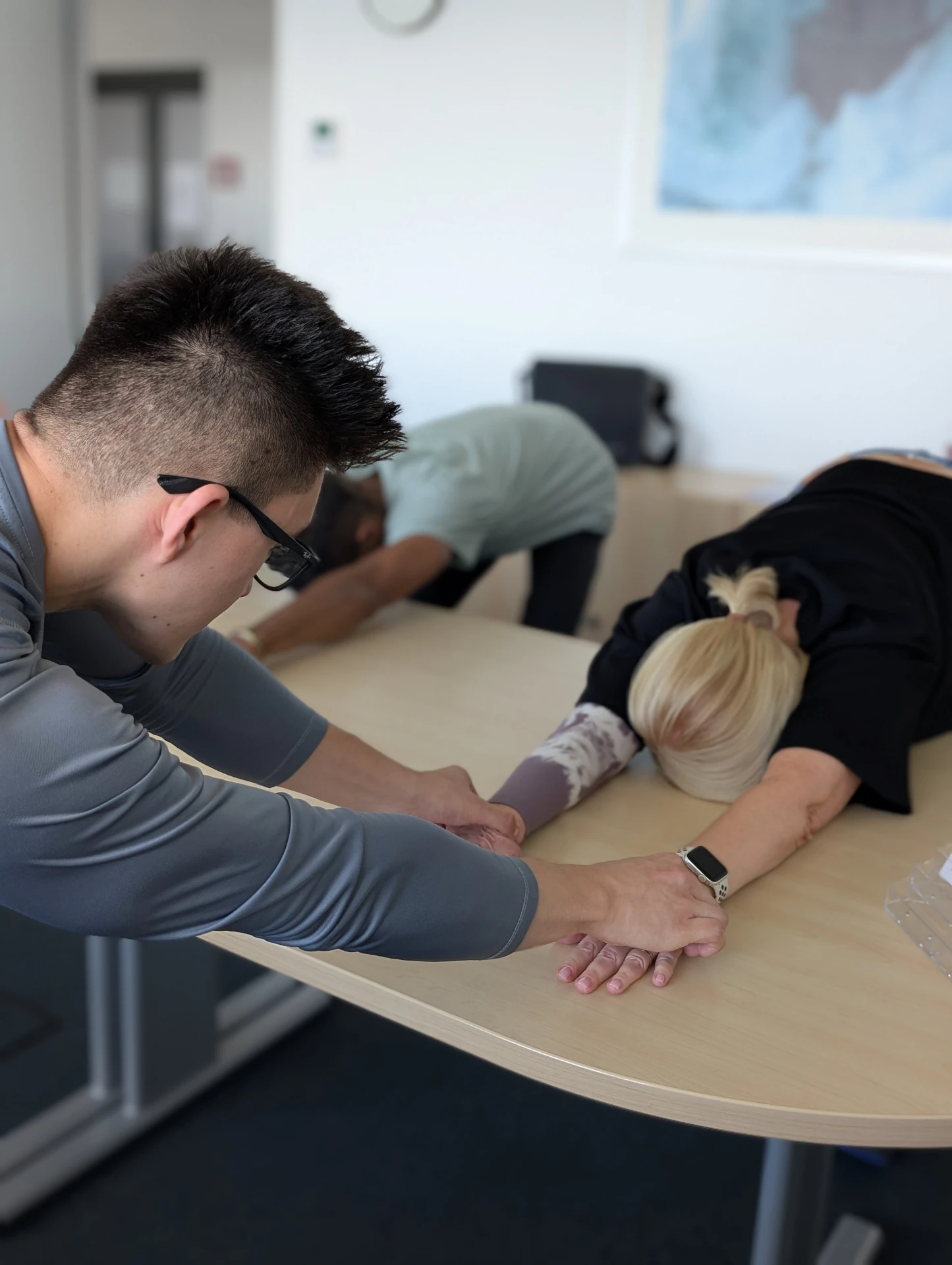 Physiotherapeutin begleitet zwei Patient:innen bei einer gerätegestützten Dehnungsübung im BGM-Kontext – Betriebliches Gesundheitsmanagement bei Fit durch Physio in Berlin.